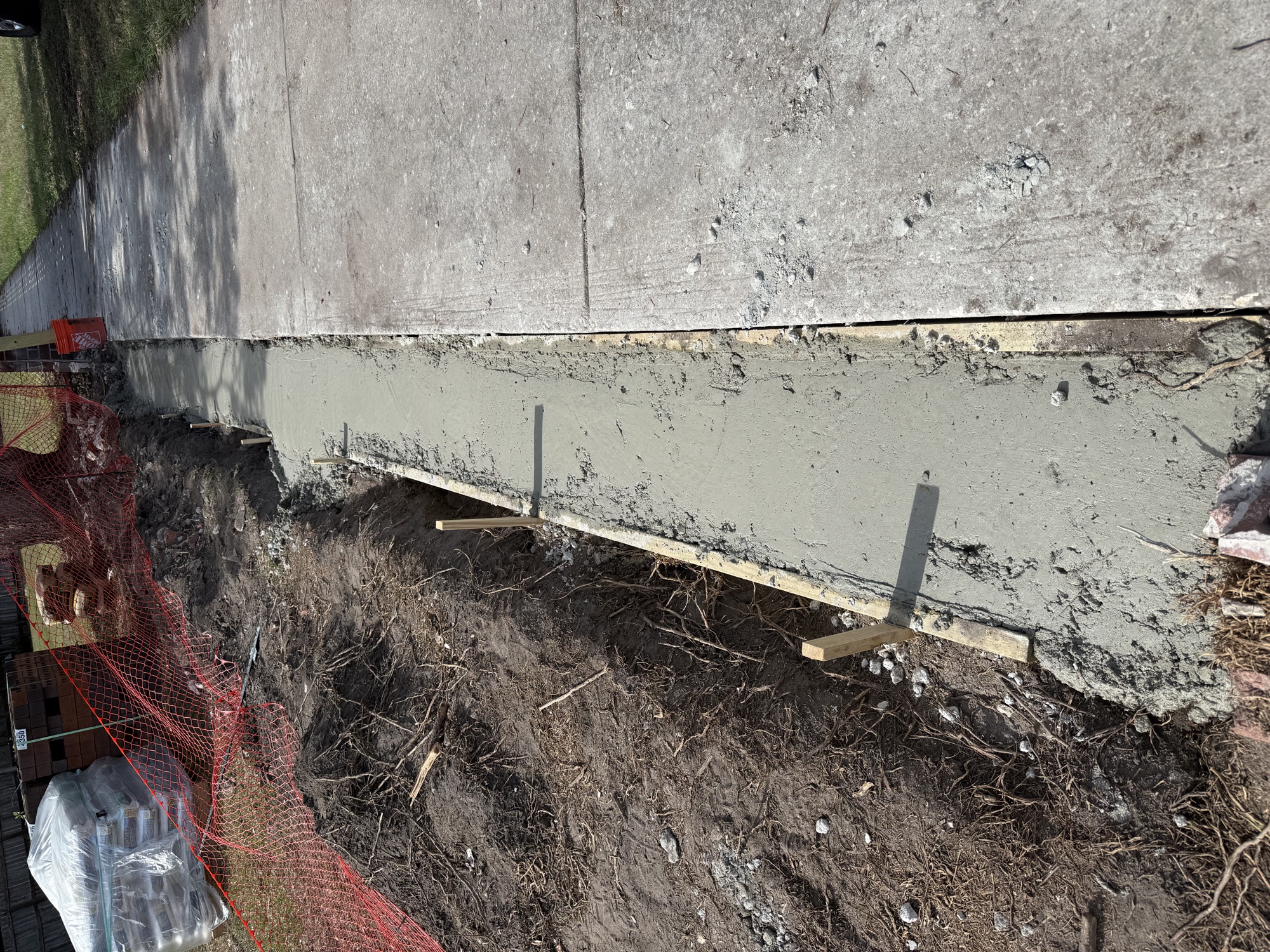Newly poured concrete wall footing beside a Surrey Ridge sidewalk